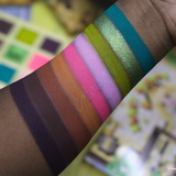 Close-up of colorful makeup swatches on a person's arm with blurred background