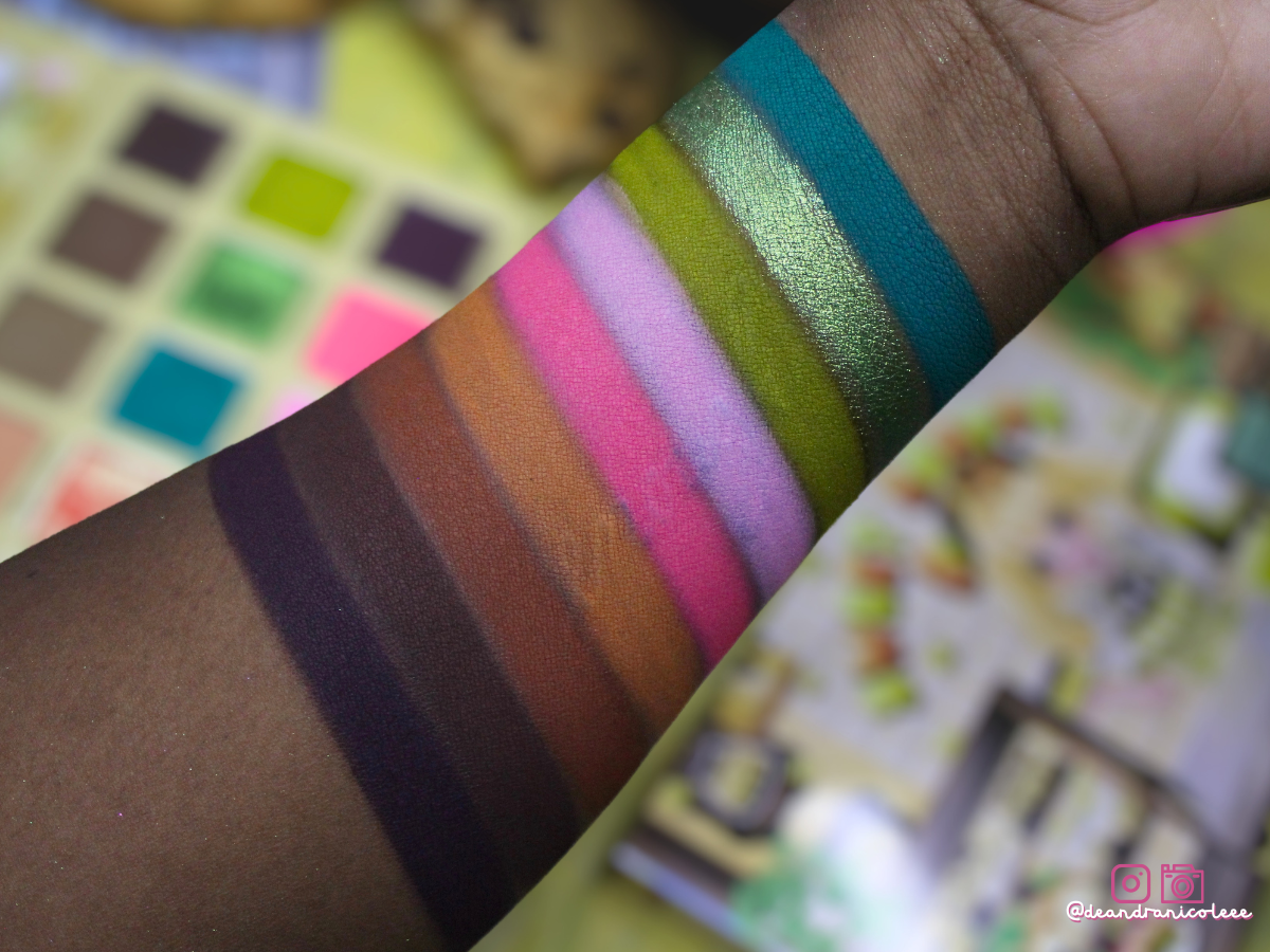 Close-up of colorful makeup swatches on a person's arm with blurred background