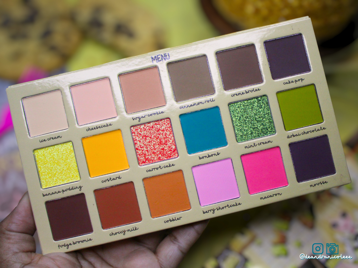 Makeup palette with various colors held by a hand against a blurred background